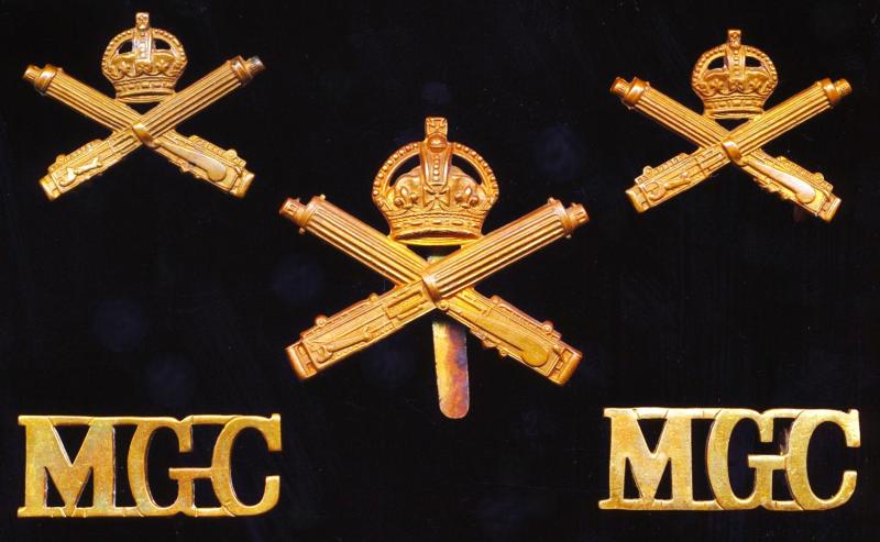 British Army: Machine Gun Corps. Set of 'King's Crown' gilding metal insignia, comprising Cap Badge (1), Collar Badges (2) & Shoulder Titles (2). Circa 1915-1922